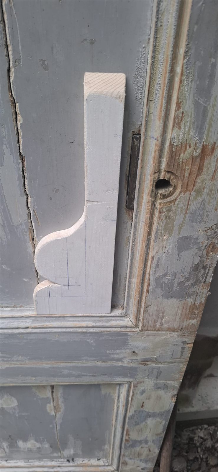 Deur met een houten sierstuk en sterk afgebladderde verf